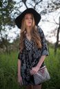 Woman in Black and White Floral Dress Wearing Black Hat Standing on Green Grass Field during