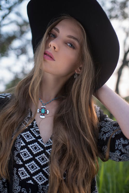 A Woman Wearing a Black Hat with Hand on Her Head