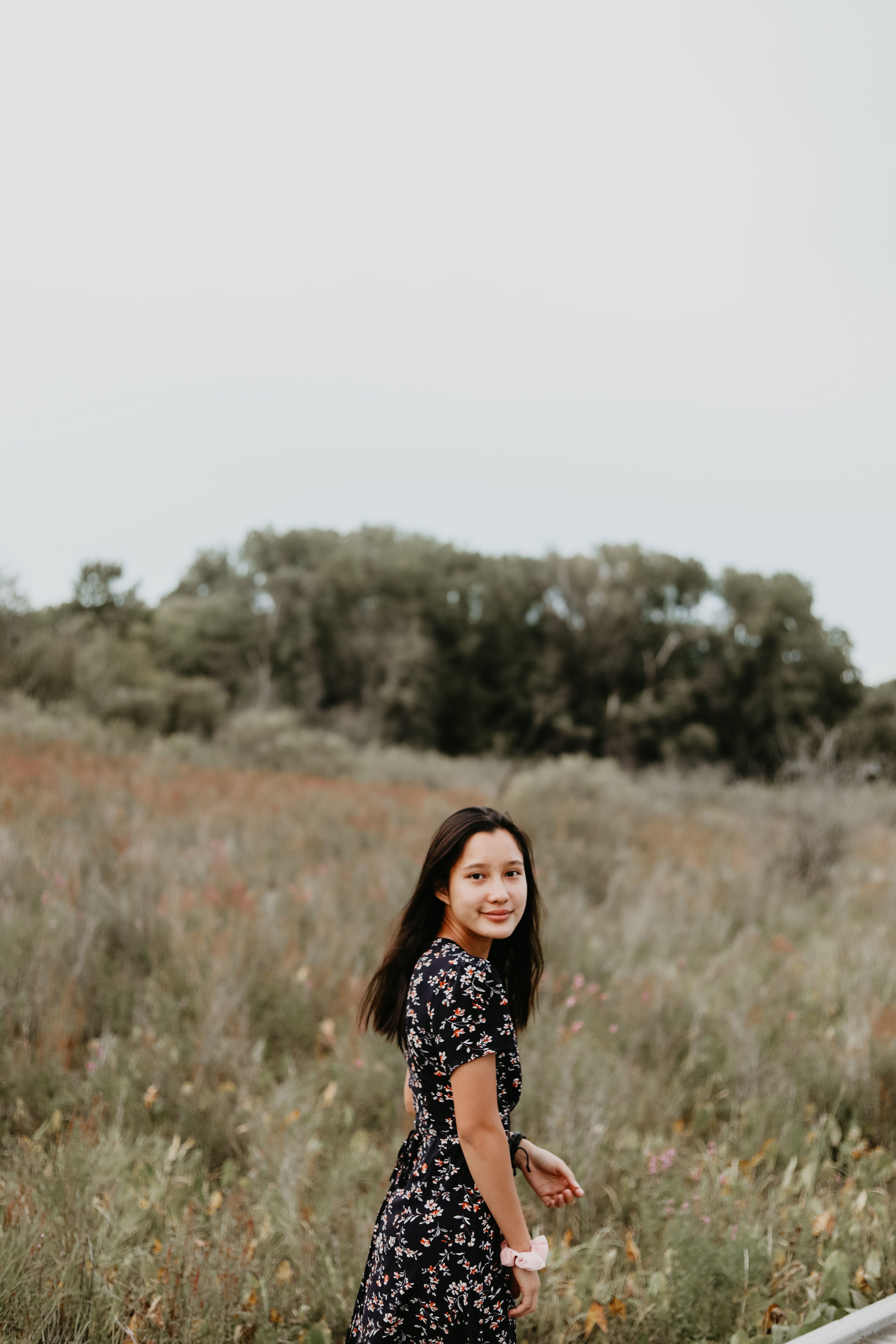 一位快乐的年轻女子在宁静的草地上漫步，享受着被大自然包围的夏日时光