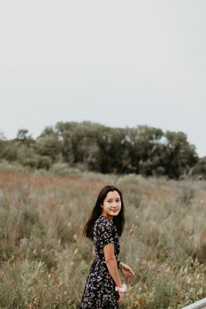 一位快乐的年轻女子在宁静的草地上漫步，享受着被大自然包围的夏日时光