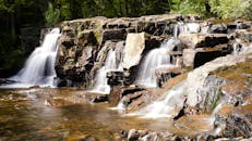 郁郁葱葱的森林中，瀑布从岩石上倾泻而下，构成了一幅宁静的景象