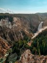 Waterfall flowing through rocky ravine with coniferous forest on sunny day