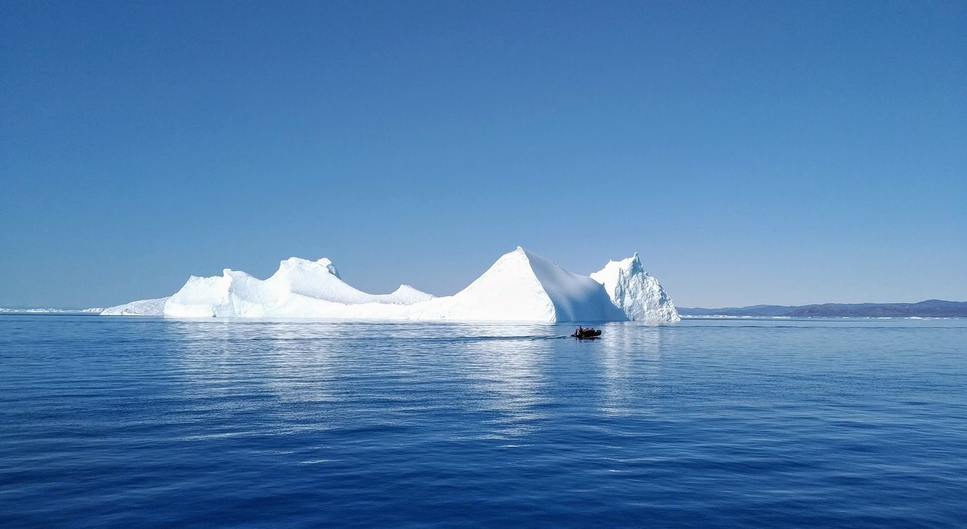 A small boat near an iceberg in the water off Ilulissat, Greenland
