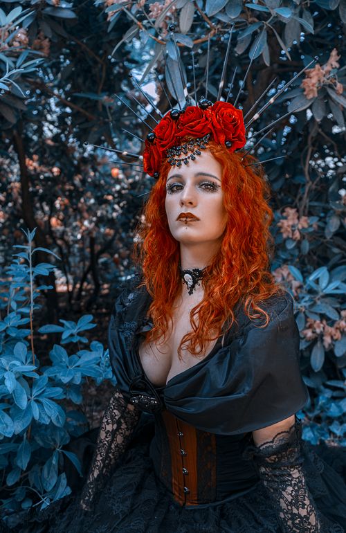 Free Dramatic gothic fashion portrait with red hair and floral headdress in German garden. Stock Photo