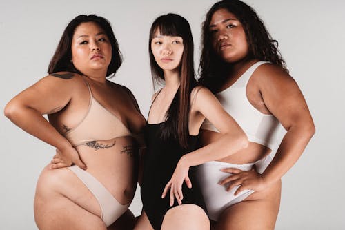 Asian women in lingerie standing against white wall in studio