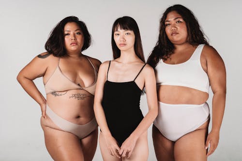 Calm Asian women in lingerie standing together in light studio