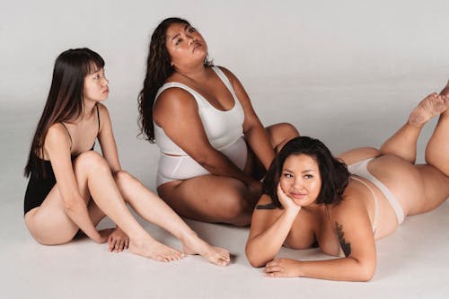 Dreamy Asian women in underwear resting on floor in studio