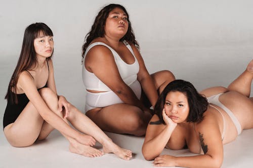 Unemotional Asian women in underwear sitting on floor in studio