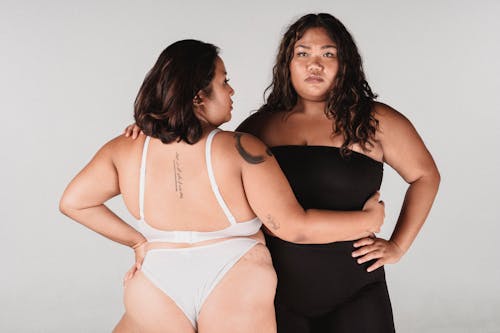 Overweight Asian women in underwear embracing in studio