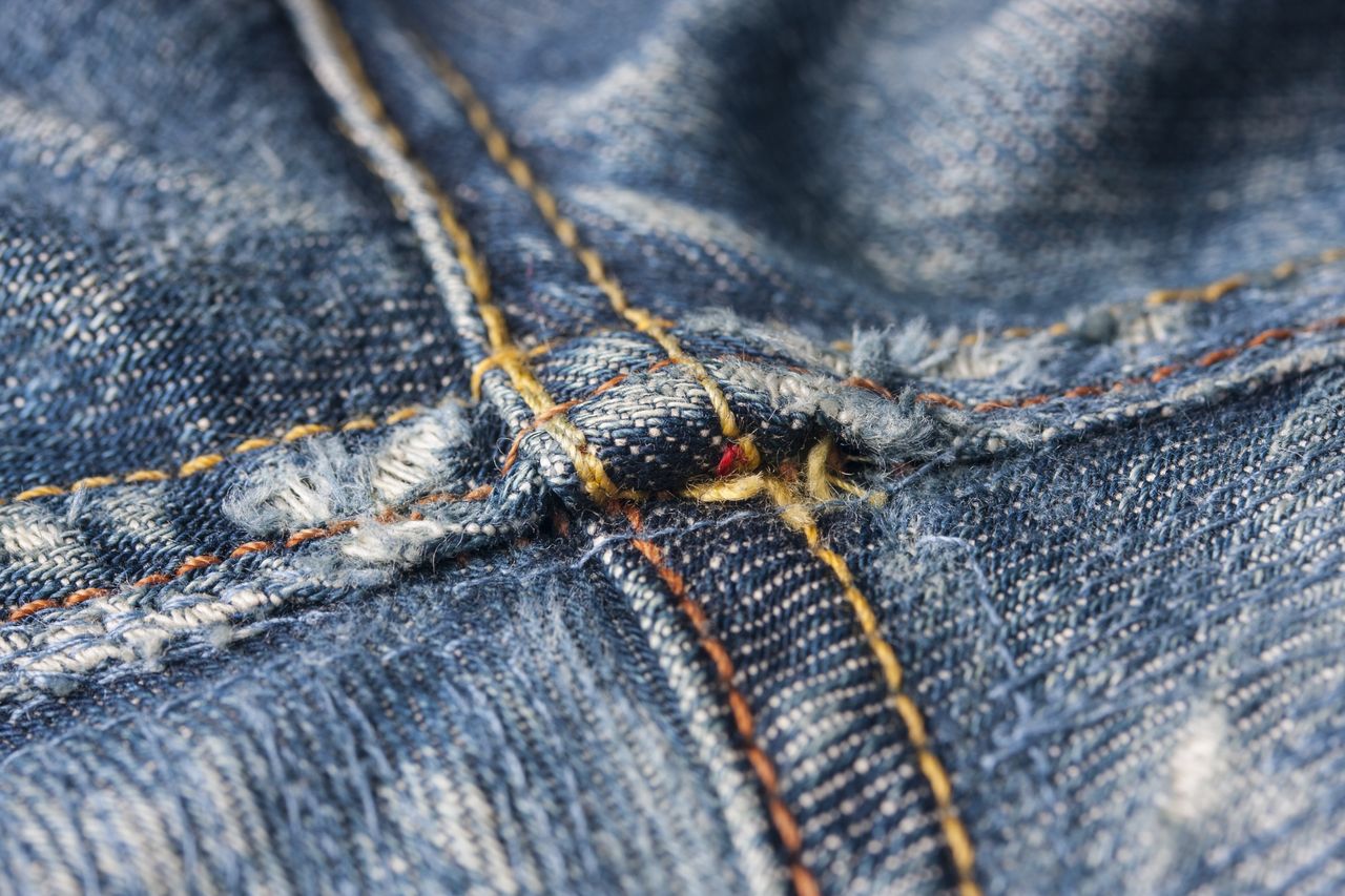 macro image highlighting the intricate stitching details of denim jean