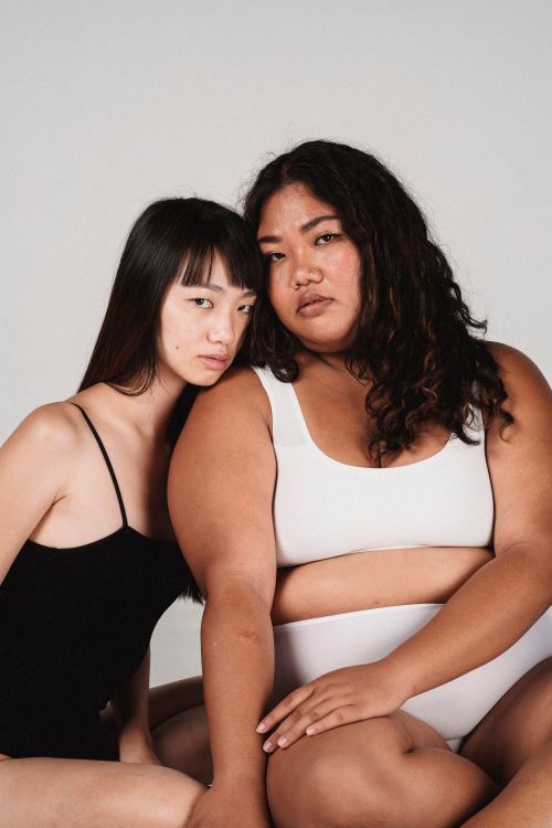 Free Young ethnic models in underwear leaning on each other while resting in studio and looking at camera Stock Photo