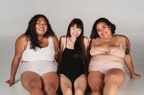 Happy Asian woman in underwear sitting in studio