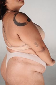 Side view of crop anonymous plus size tanned female standing on white background