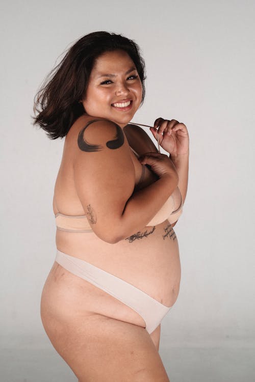 Cheerful overweight Asian woman with tattoo smiling