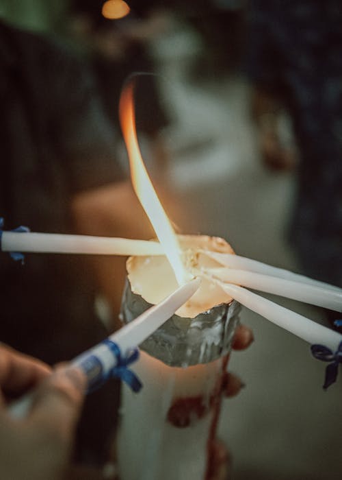 People Lighting Candles From Flame of Big Candle