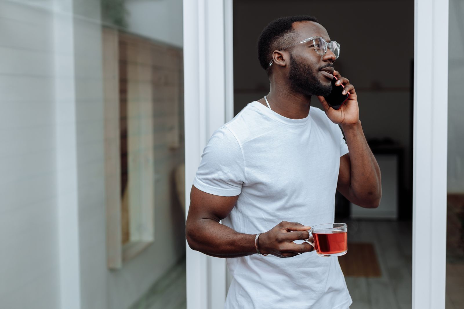 Man in glasses on a phone call outdoors with his tea