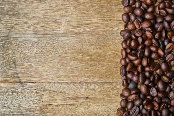Fresh coffee beans scattered on a rustic wooden table, perfect for warm, natural themes.