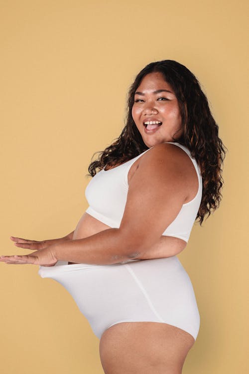 Cheerful Asian plus size model smiling in studio