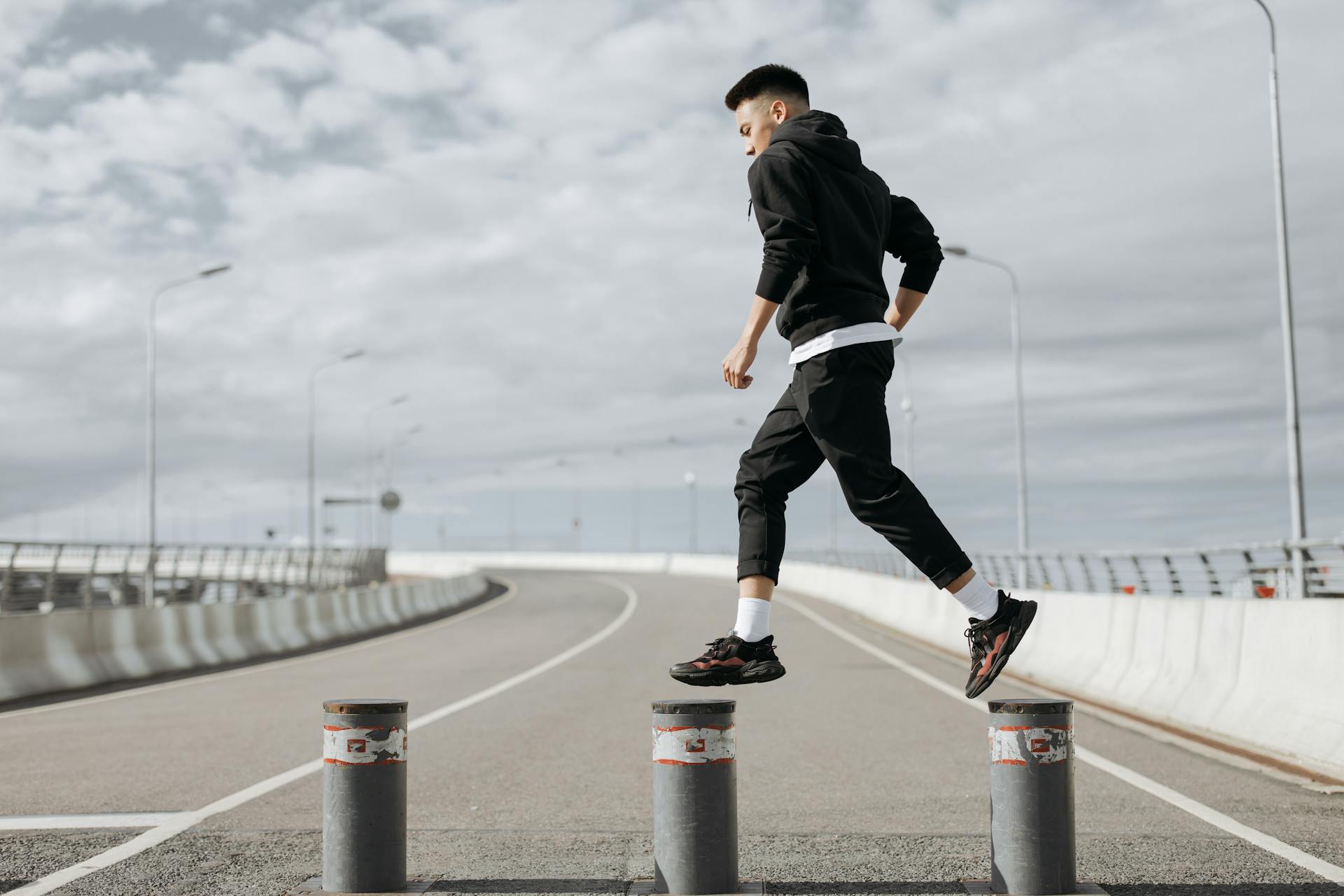 A Man in Black Jacket and Black Pants Working Out on the Road