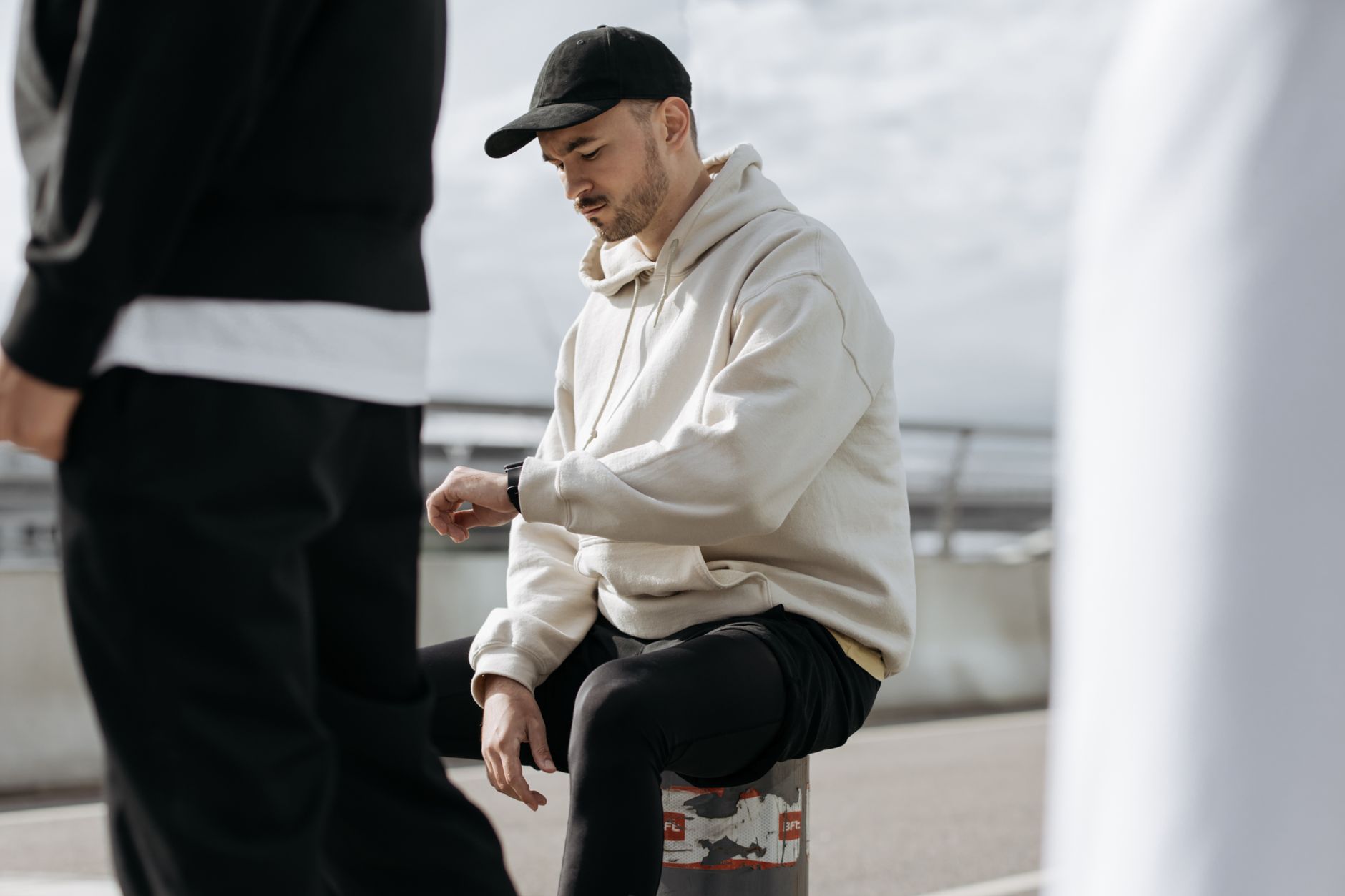 jeune homme en hoodie oversize beige et casquette noire, style streetwear Y2K décontracté