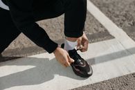 特写镜头：一个人在户外人行道上系运动鞋，人行道带有道路标记