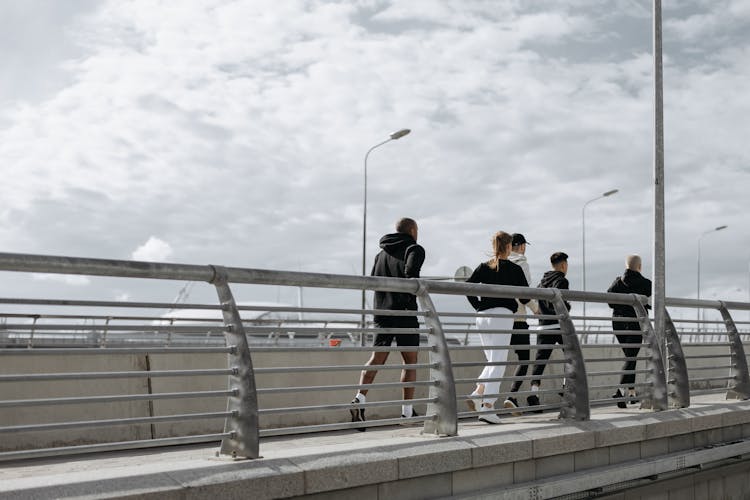 People Jogging On Gray Concrete Bridge