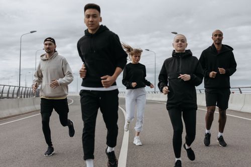 Free A diverse group of adults jogging together outdoors on a cloudy day. Stock Photo