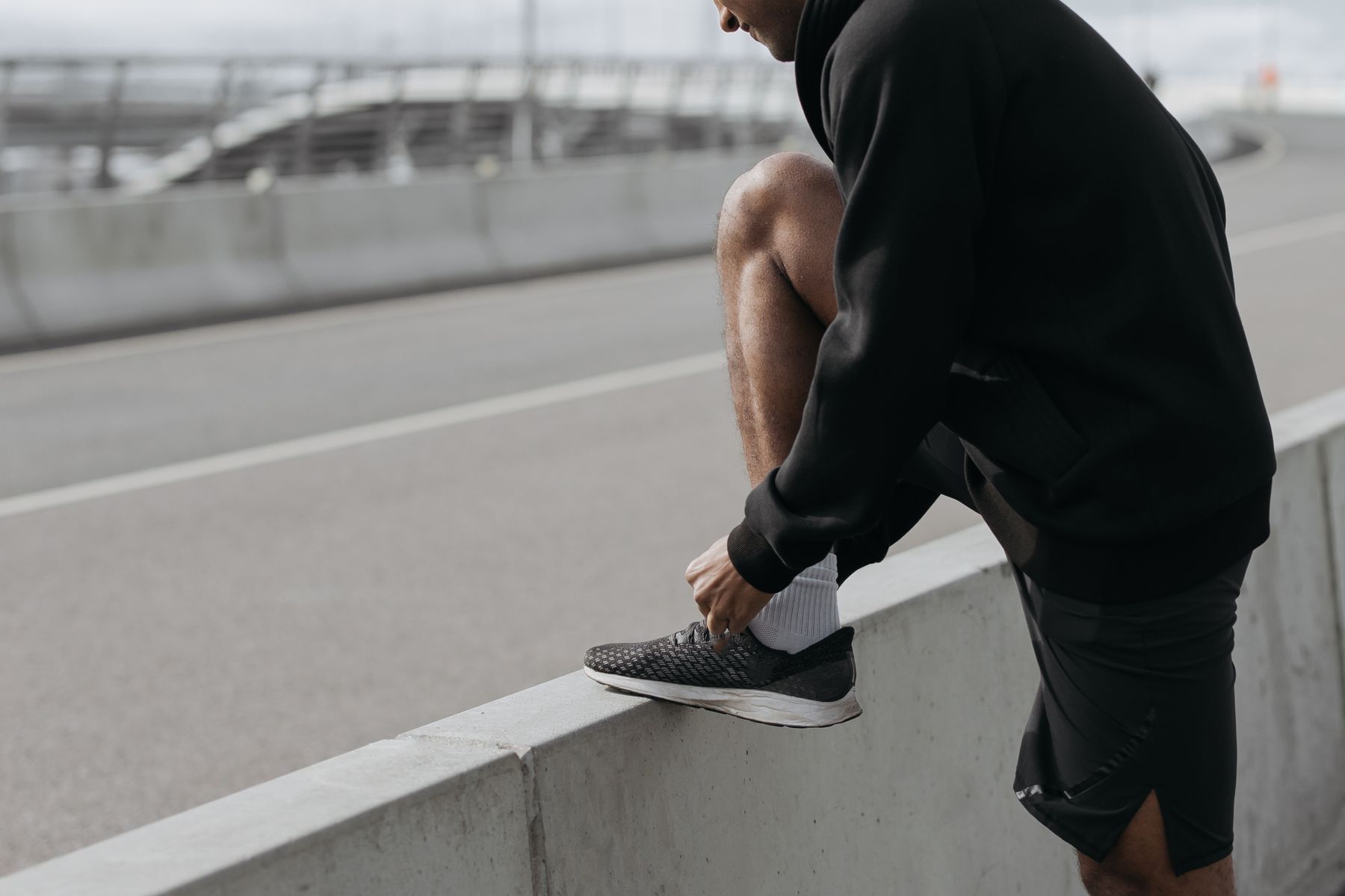 Person tying a grey sneaker outdoors