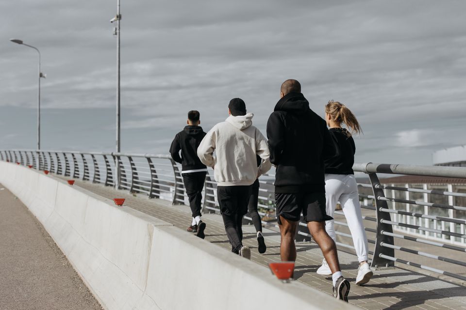 A group of adults running together across a city bridge