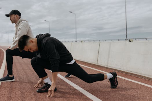 Two men stretching on an outdoor track, preparing for a workout session.