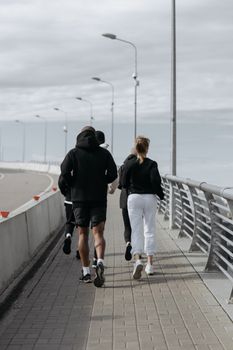 一群慢跑者在城市人行道上奔跑，头顶阴云密布的天空，共同拥抱健身