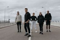 五位不同朋友穿着运动服，在空荡荡的城市道路上自信地摆姿势