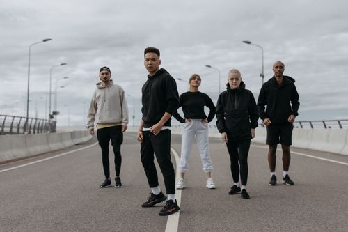 Free Five diverse friends in sportswear posing confidently on an empty urban road. Stock Photo