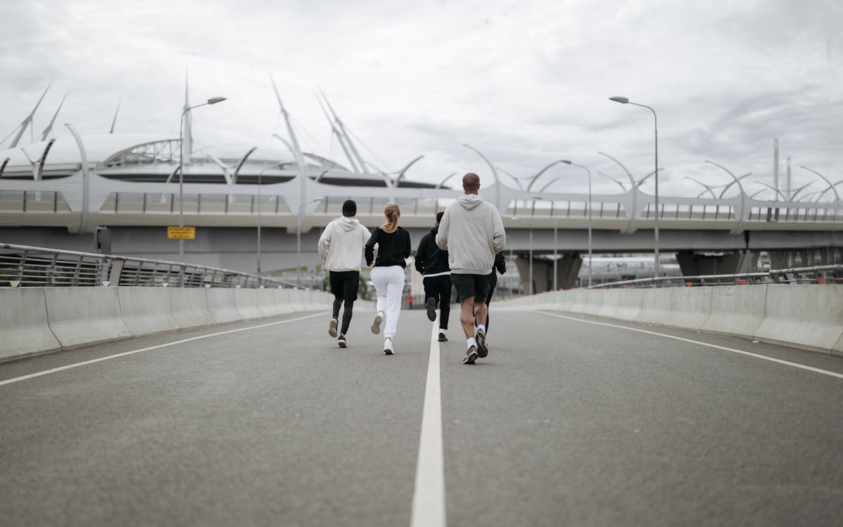 Diverse group jogging on a modern bridge in sportswear, promoting health.
