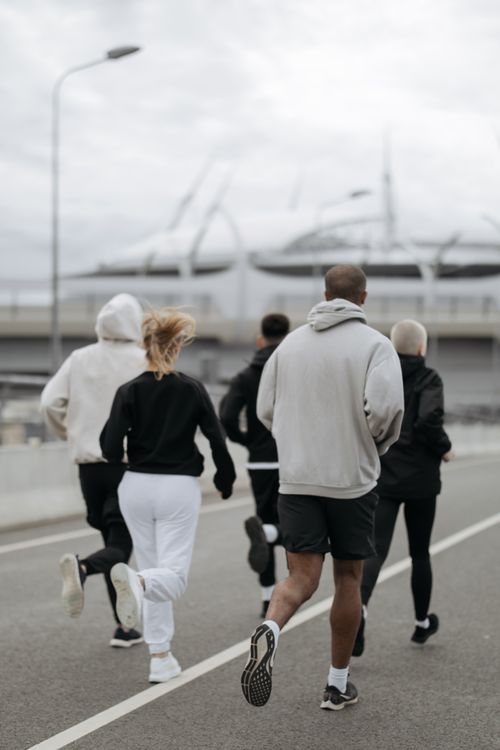 Free Five adults jogging outdoors in an urban area, promoting fitness and teamwork. Stock Photo