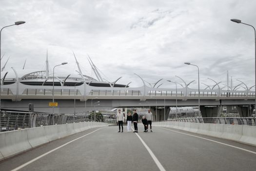 一群朋友走在城市里一座现代化桥梁附近的空荡道路上