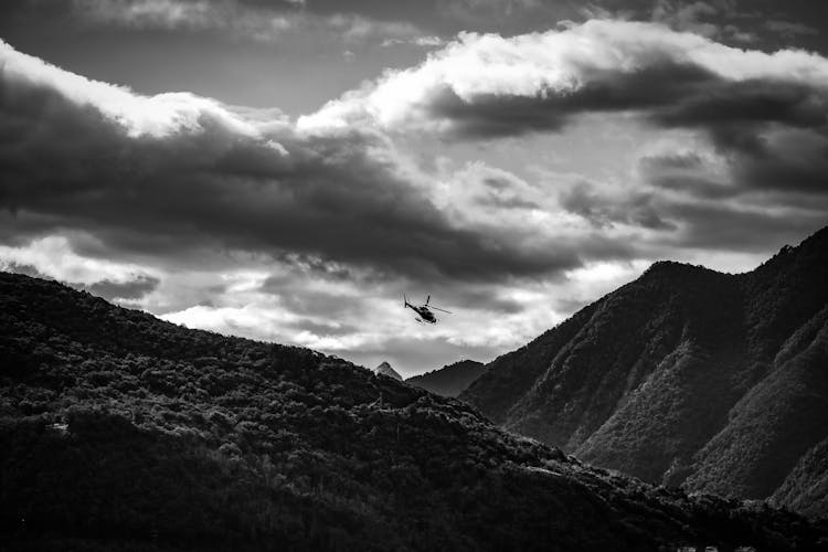 Helicopter Flying Over High Mountains Covered With Forest