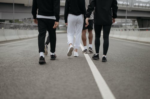 Free People in Their Activewear Walking on an Asphalt Road Stock Photo