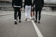 城市道路上，一群身着休闲运动服的人正向前走去，他们的背影凸显了城市健身文化