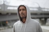 一名身穿灰色连帽衫的男子在城市街头的特写镜头中，看起来若有所思