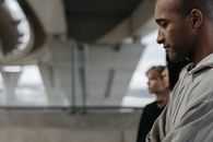 现代桥下，一个男人沉思的侧面，背景是模糊的人影