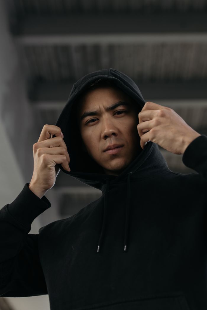 Model mengenakan hoodie hitam tanpa logo