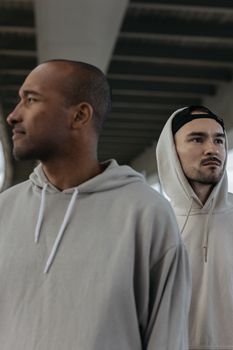 两名穿着连帽衫的男子站在桥下，目光移开