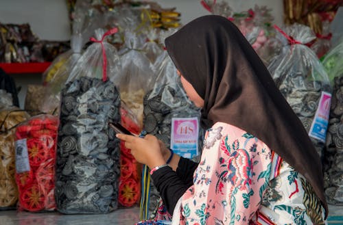 A Woman in a Hijab Texting on Her Cellphone