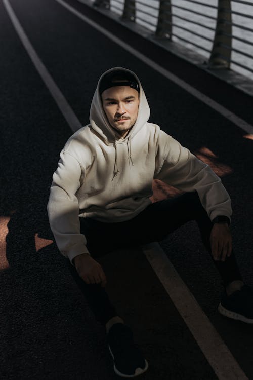 Free A Man in a Hoodie Jacket Sitting on the Road Stock Photo