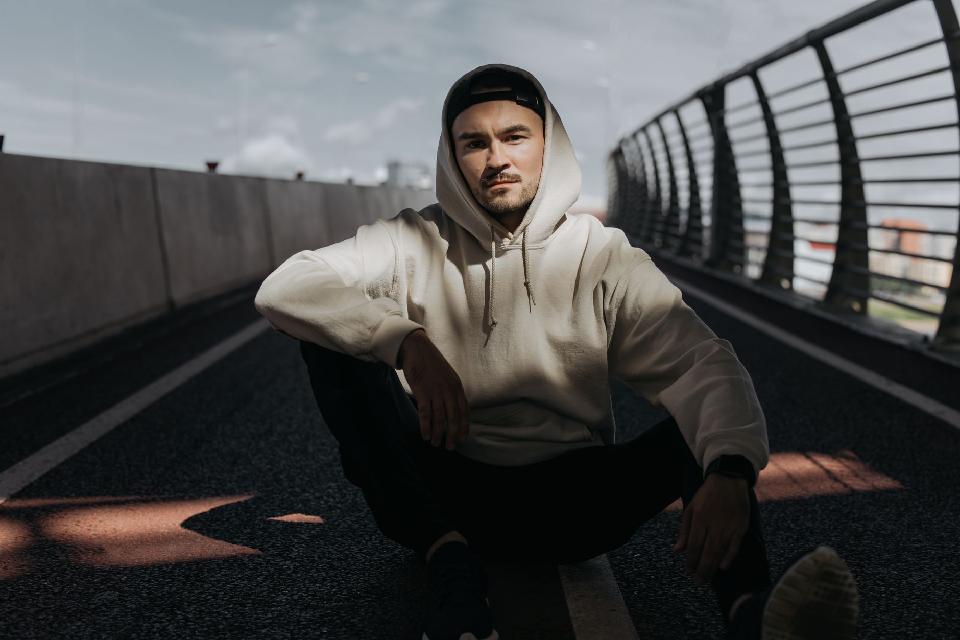 Jeune homme en hoodie streetwear écru dans un cadre urbain