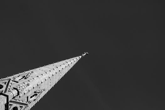 Black and white photo of a gothic church steeple reaching into a dark sky.