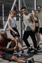 五名穿着运动服的年轻人在城市里靠着金属栅栏摆姿势