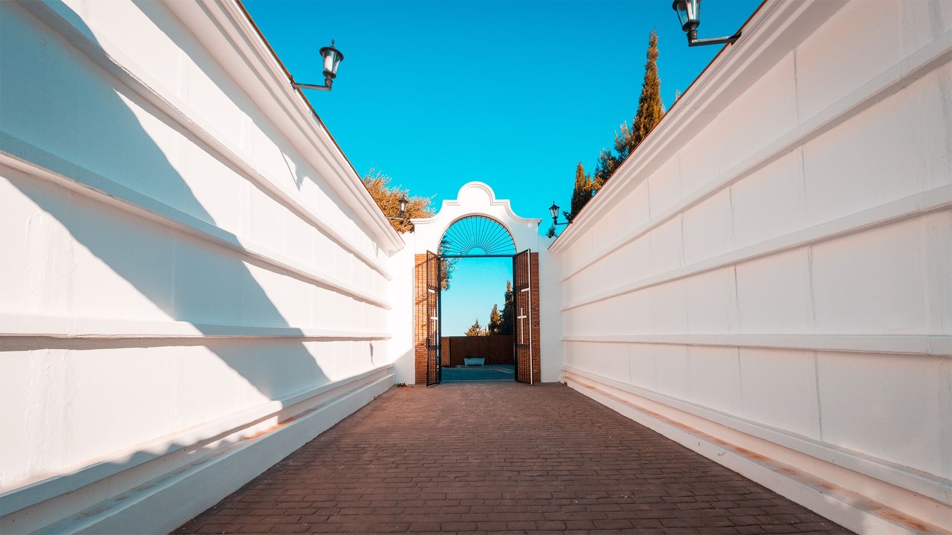 White architectural entrance with a blue sky backdrop and vintage lamps.