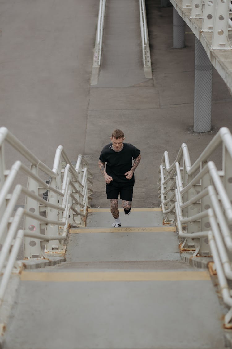 A Man In Black Shirt Running On The Concrete Stairs